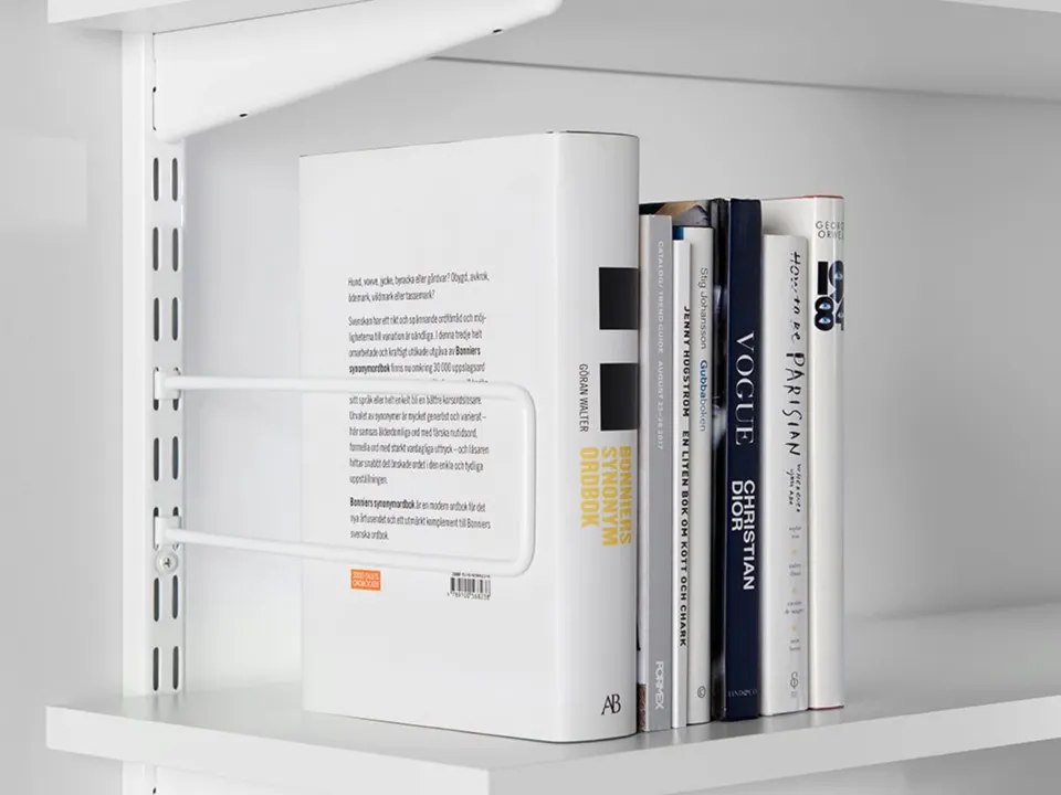 Крупный план белой полки Elfa с книгами и держателем